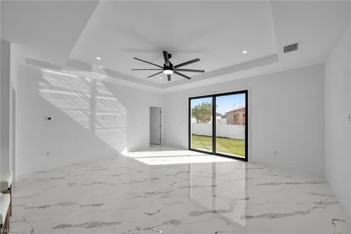 Empty room featuring a raised ceiling, ceiling fan, recessed lighting, baseboards, and marble finish flooring