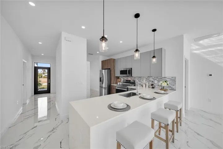 Kitchen featuring appliances with stainless steel finishes, recessed lighting, light countertops, decorative backsplash, and baseboards