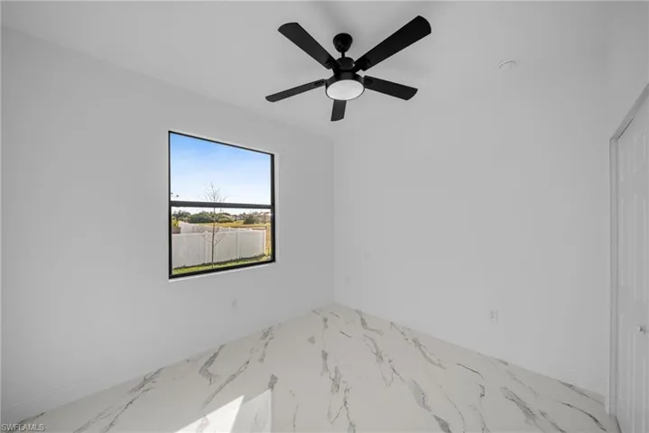 Spare room with marble finish floors, baseboards, and ceiling fan
