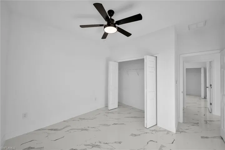 Unfurnished bedroom with baseboards, light marble finish flooring, and a closet