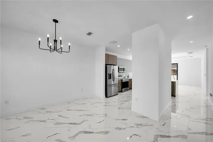 Unfurnished dining area with baseboards, recessed lighting, a chandelier, and light marble finish flooring