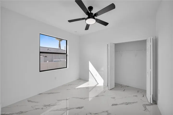 Unfurnished bedroom with ceiling fan, a closet, marble finish floors, and baseboards