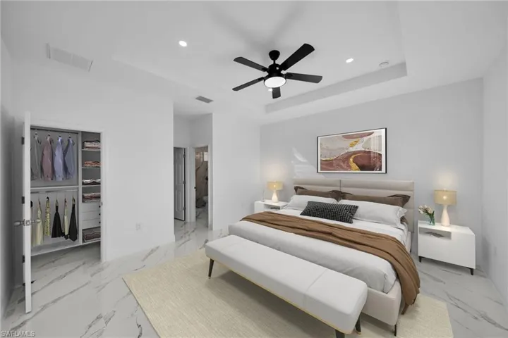 Bedroom featuring a tray ceiling, recessed lighting, marble look tile flooring, a spacious closet, and baseboards