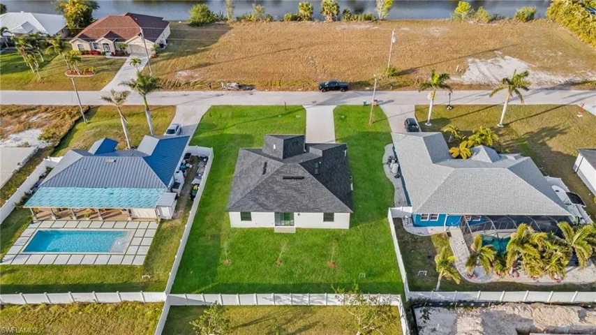 Aerial perspective of suburban area with a nearby body of water and a pool
