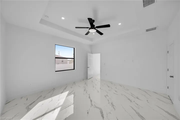 Unfurnished room with a tray ceiling, recessed lighting, baseboards, ceiling fan, and marble finish floors