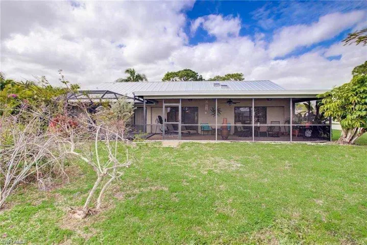 Rear view of property featuring a yard and a sunroom