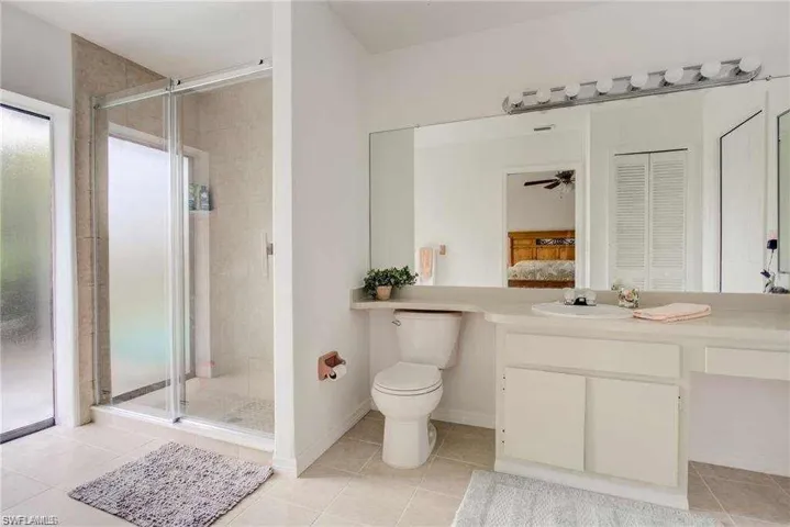 Bathroom featuring tile patterned flooring, a shower with door, vanity, and toilet
