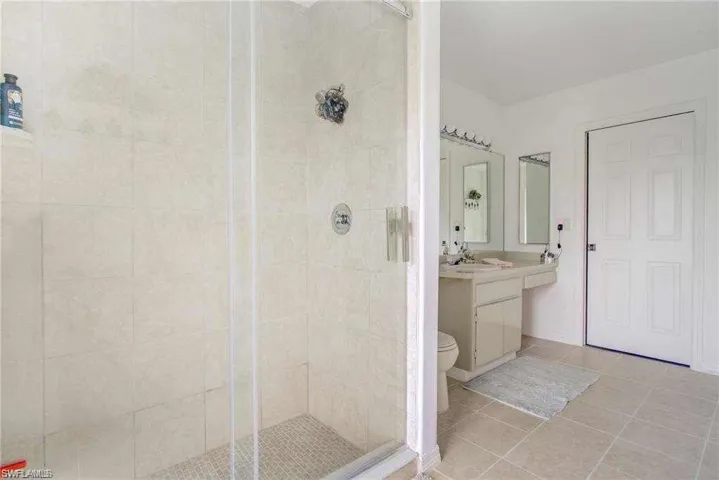 Bathroom featuring tile patterned flooring, vanity, toilet, and a shower with shower door