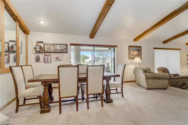 Dining room with vaulted ceiling with beams and light carpet