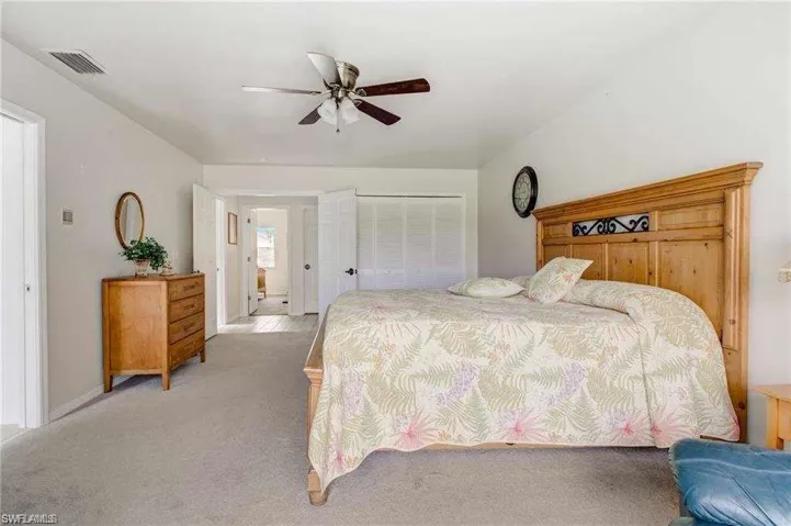 Bedroom with a closet, ceiling fan, and light colored carpet