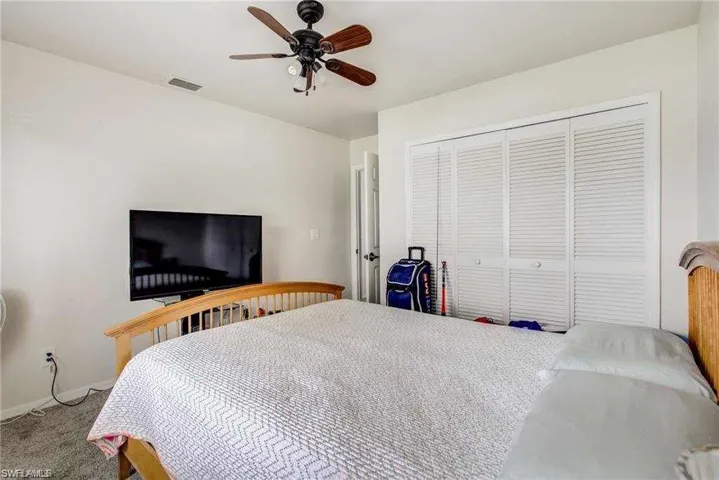 Carpeted bedroom with ceiling fan and a closet