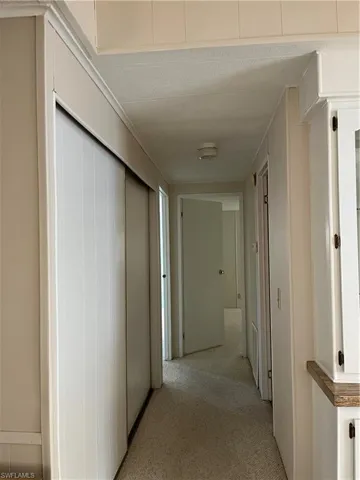 Hallway featuring light carpet