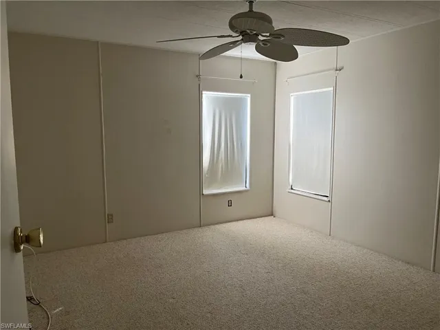 Carpeted empty room featuring a ceiling fan