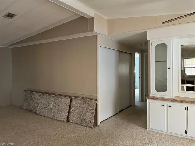 Hallway featuring vaulted ceiling and light colored carpet