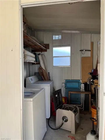 Washroom featuring concrete flooring, independent washer and dryer, and wood walls