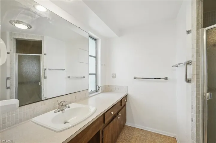 Bathroom featuring vanity, tasteful backsplash, and a shower with door