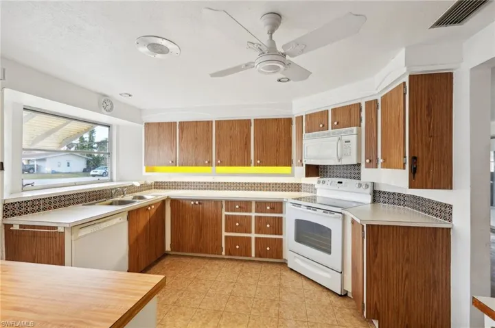 Kitchen featuring decorative backsplash, white appliances, ceiling fan, and sink