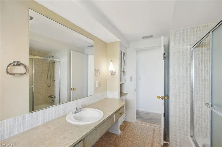 Bathroom with vanity, enclosed tub / shower combo, and backsplash