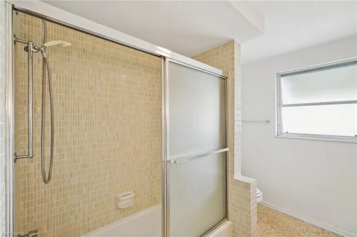 Bathroom featuring toilet and shower / bath combination with glass door