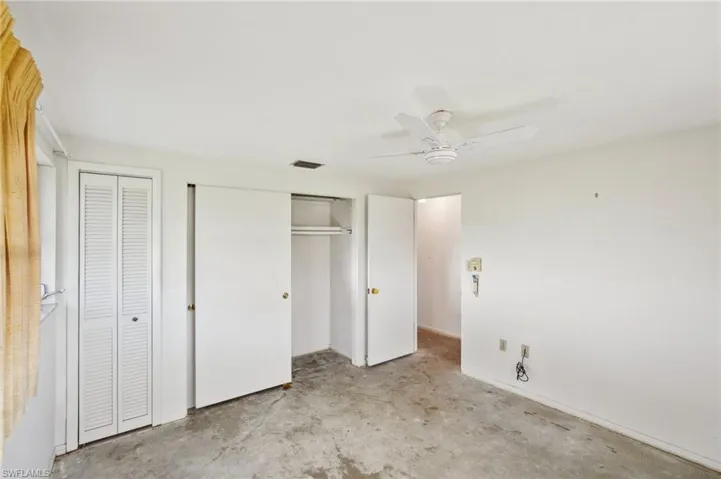 Unfurnished bedroom with ceiling fan and two closets