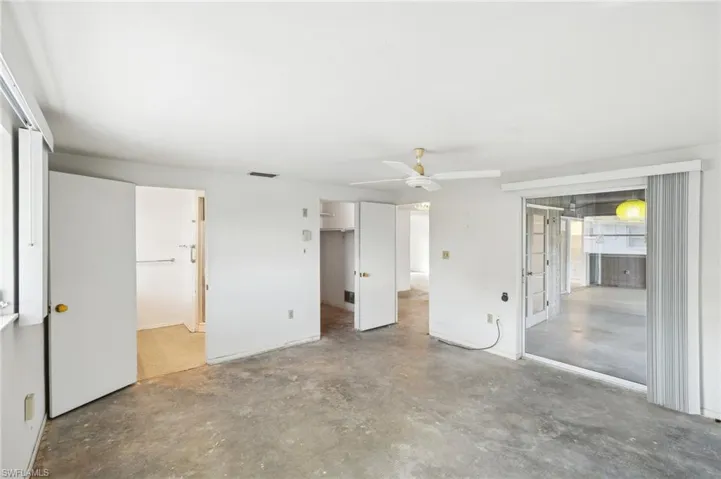 Unfurnished bedroom featuring ceiling fan, concrete flooring, ensuite bathroom, and a closet