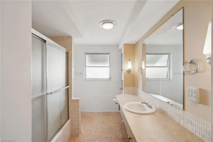 Bathroom featuring vanity and bath / shower combo with glass door