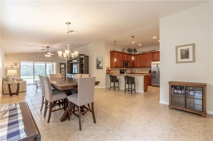 Dining area with ceiling fan with notable chandelier, light tile patterned flooring, and vaulted ceiling