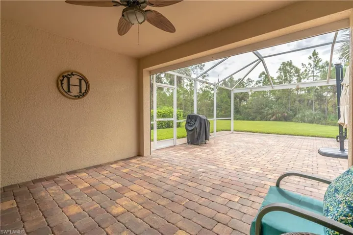 View of patio featuring glass enclosure, ceiling fan, and area for grilling