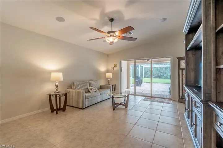 Tiled living room featuring ceiling fan and vaulted ceiling