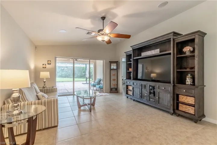 Living room featuring light tile patterned floors, lofted ceiling, and ceiling fan