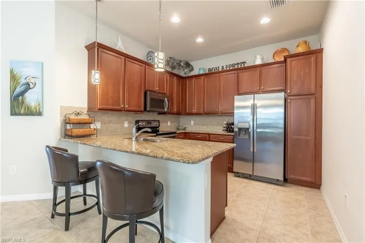 Kitchen with stainless steel appliances, backsplash, kitchen peninsula, and decorative light fixtures