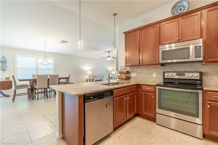 Kitchen with tasteful backsplash, kitchen peninsula, pendant lighting, stainless steel appliances, and ceiling fan
