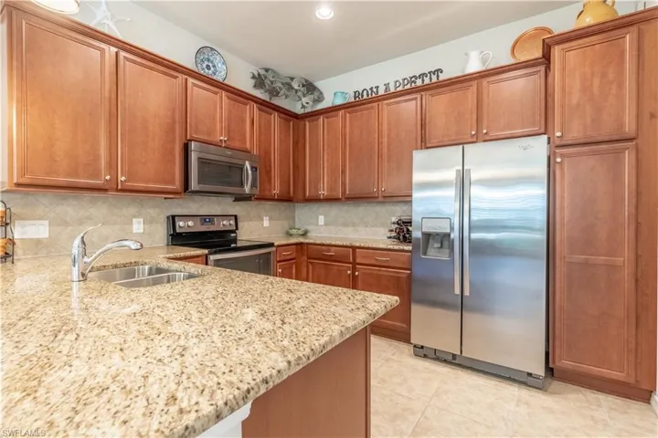 Kitchen with backsplash, stainless steel appliances, light stone counters, and sink