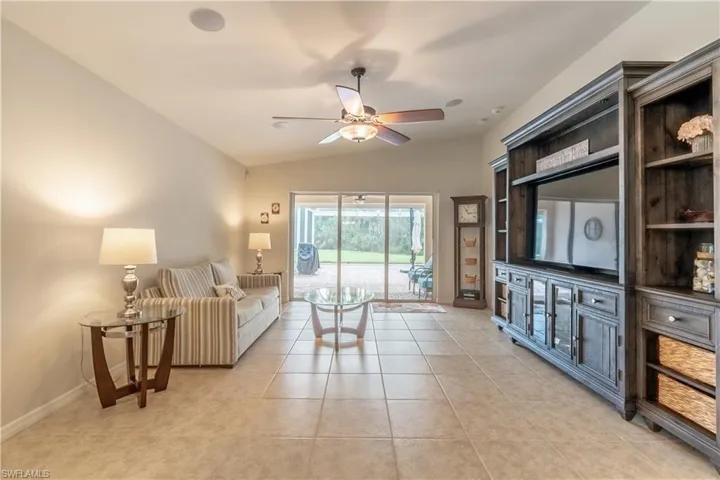 Living room with vaulted ceiling, ceiling fan, and light tile patterned floors