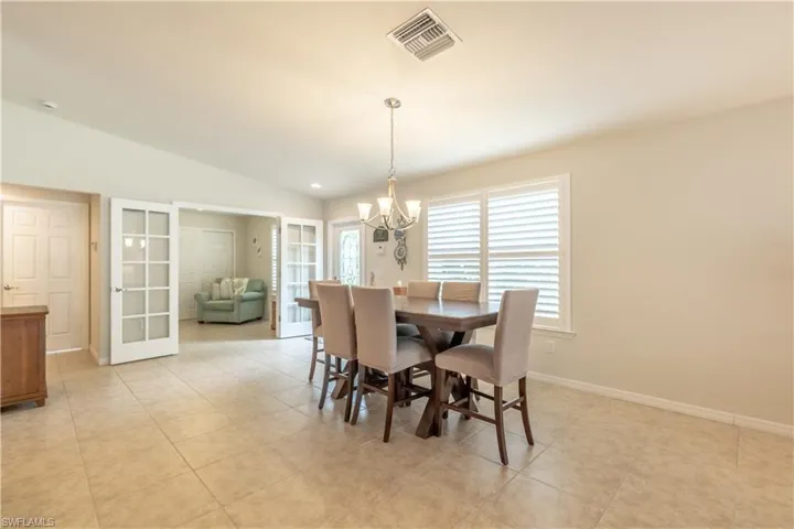 Dining area with light tile patterned floors, a notable chandelier, and vaulted ceiling