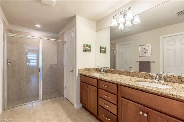 Bathroom featuring tile patterned flooring, vanity, and a shower with shower door