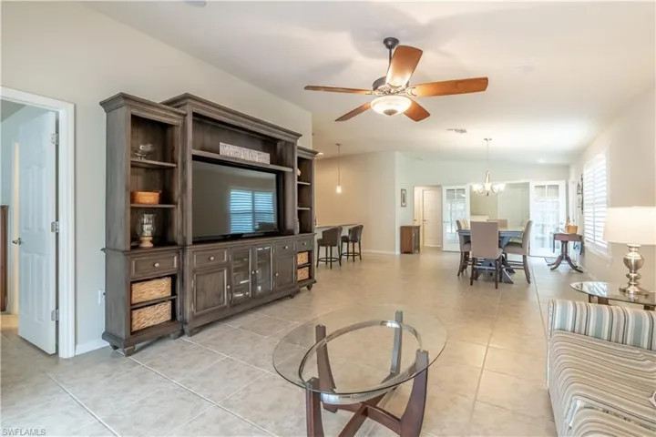 Living room featuring light tile patterned floors, lofted ceiling, and ceiling fan