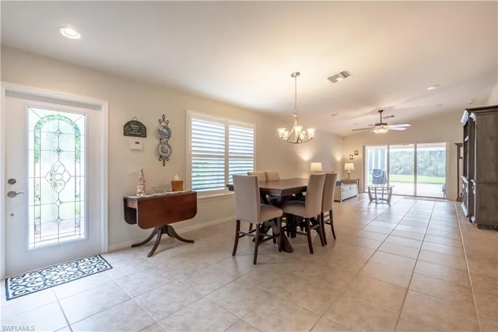 Dining area featuring ceiling fan with notable chandelier, light tile patterned floors, and a healthy amount of sunlight
