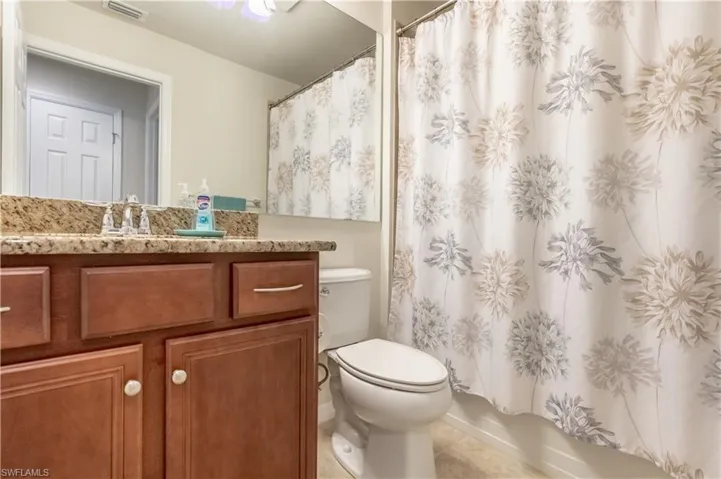 Full bathroom with shower / bath combo with shower curtain, tile patterned flooring, vanity, and toilet