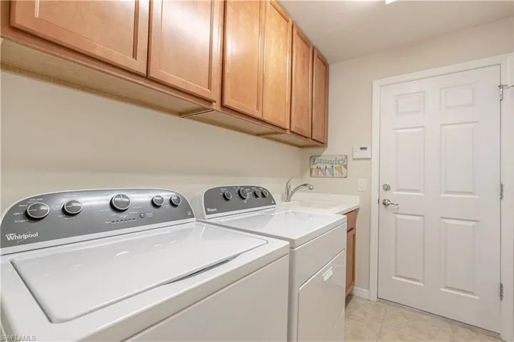 Washroom featuring light tile patterned floors, separate washer and dryer, cabinets, and sink