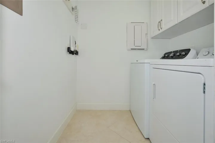 Washroom featuring cabinet space, washer and dryer, and light tile patterned floors