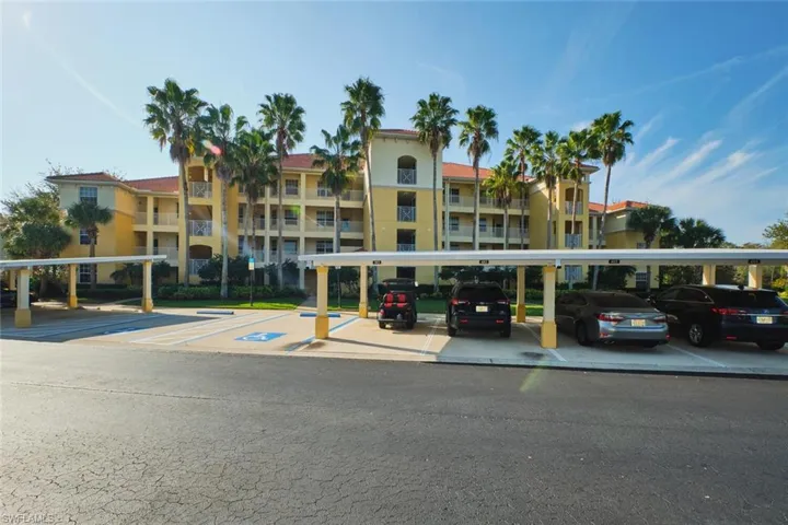 View of apartment building / complex featuring covered parking