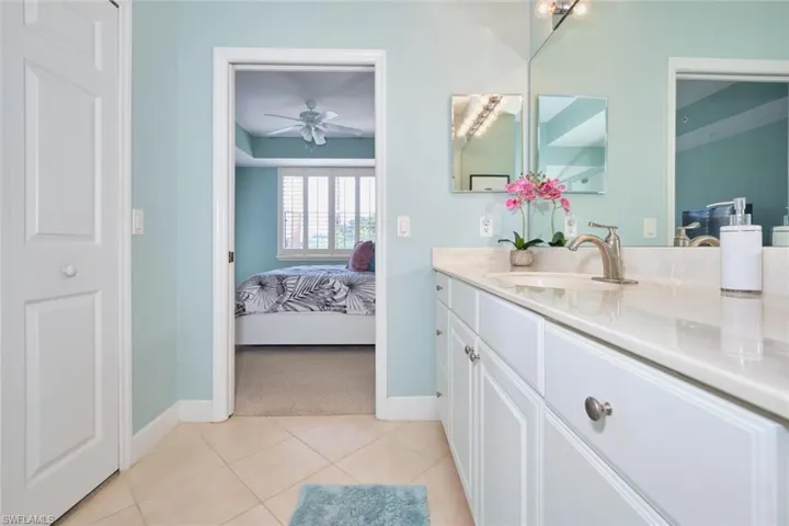 Ensuite bathroom with vanity, light tile patterned floors, and ceiling fan