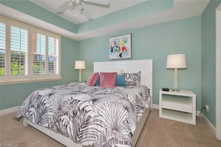 Bedroom featuring carpet, a tray ceiling, and ceiling fan