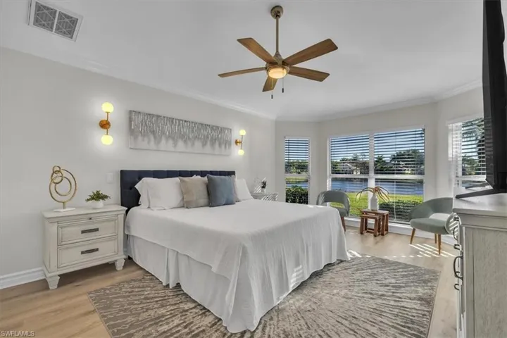 Bedroom with light wood-style floors, crown molding, and ceiling fan