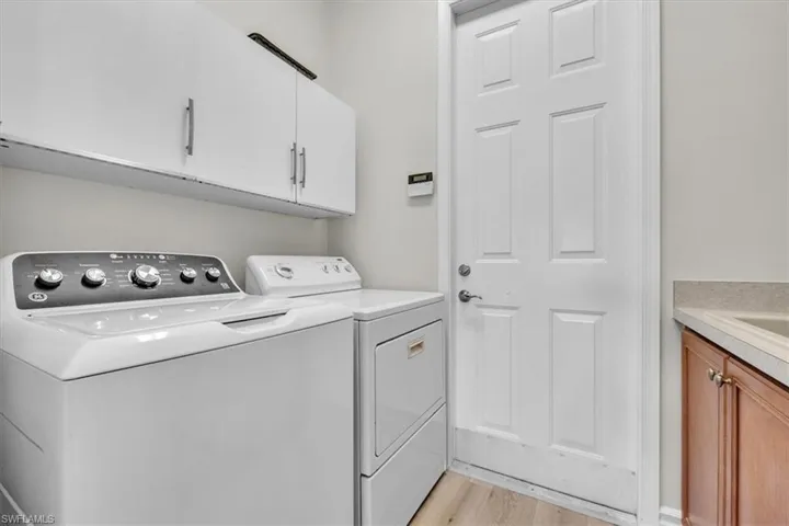 Laundry area featuring cabinet space, light wood finished floors, and washing machine and clothes dryer