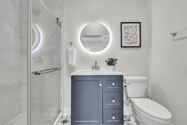 Bathroom featuring vanity, a shower stall, and a textured wall