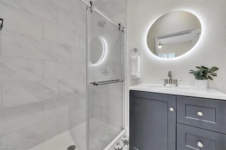 Bathroom featuring a textured wall, vanity, and a stall shower