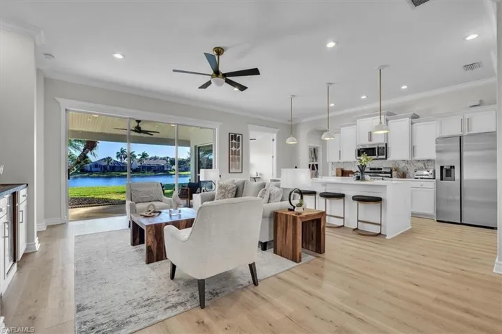 Dining area with light wood-style floors, recessed lighting, crown molding, a water view, and a ceiling fan