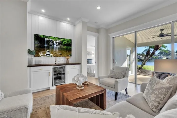 Living room featuring light wood-type flooring, beverage cooler, a ceiling fan, recessed lighting, and crown molding